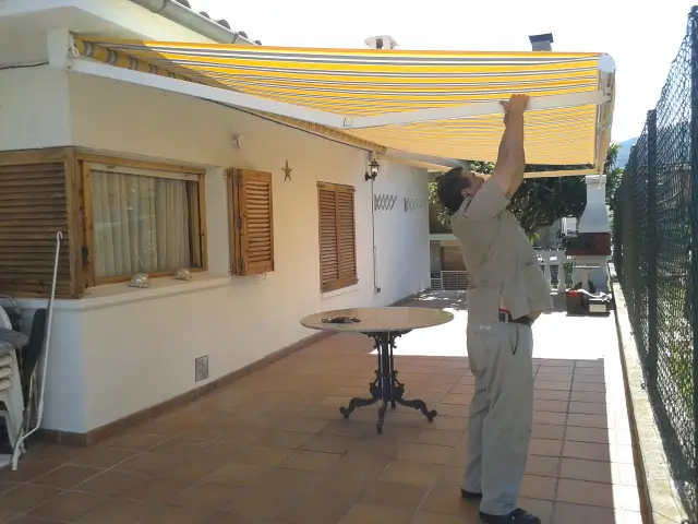 Se ve al Ángel de Rederi colocando toldos en una casa de Ripoll