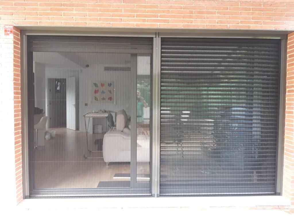 Mostramos cómo queda una de nuestras mosquiteras puestas. Se ve un ventanal deslizante con una gran mosquitera doble.