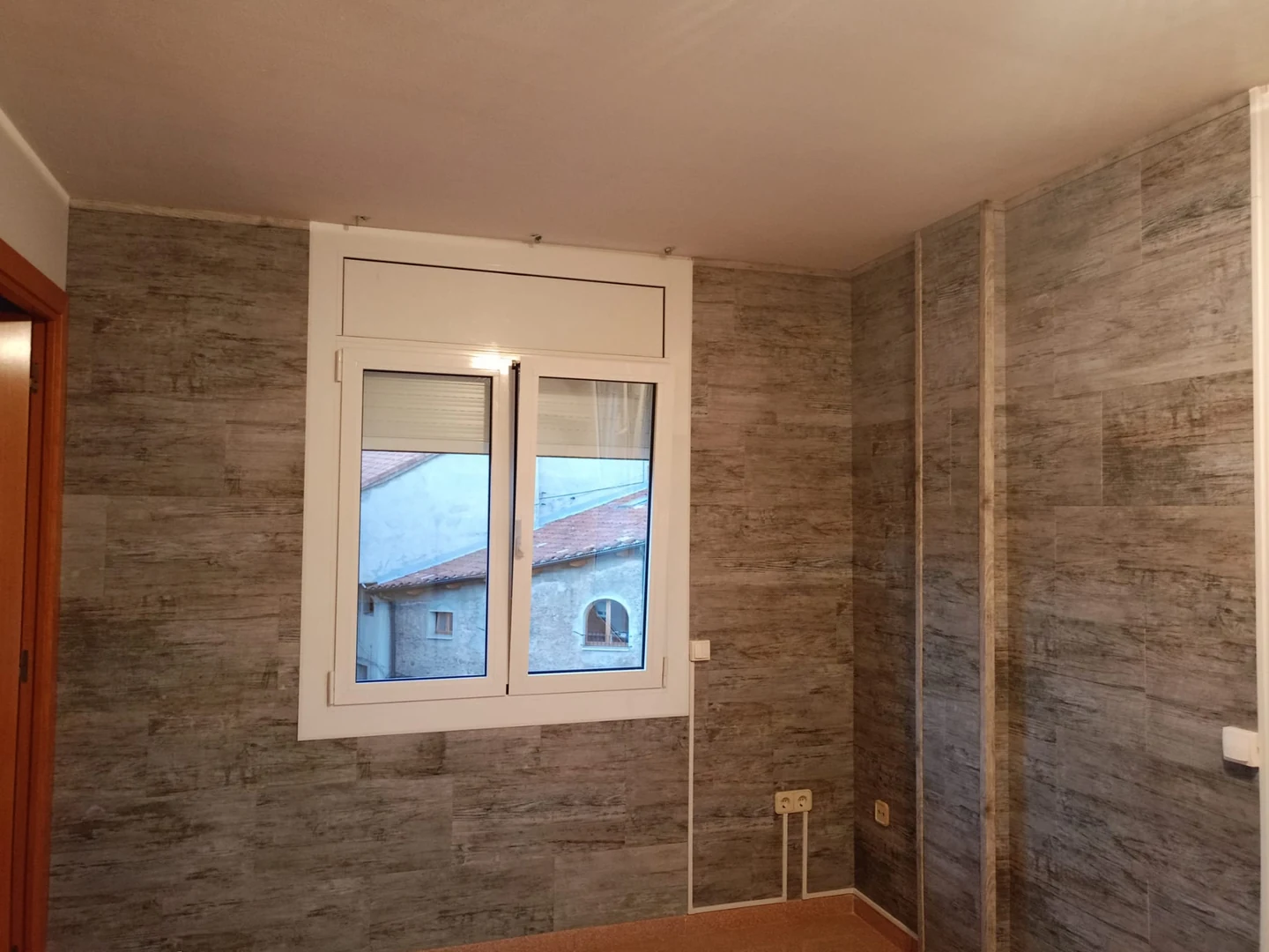 Paredes con revestimiento efecto madera gris terminado alrededor de una ventana blanca